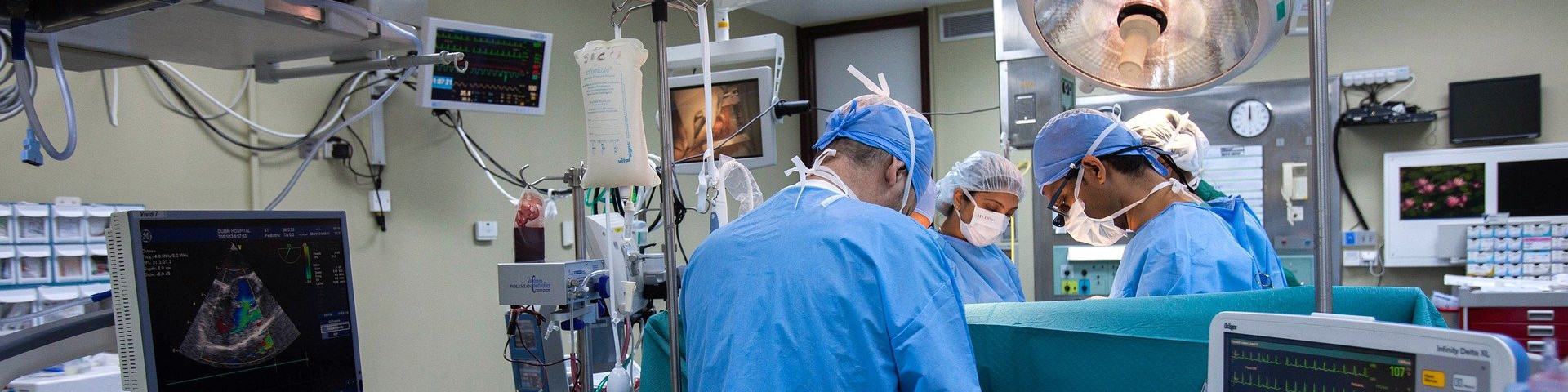 KI generiert: Das Bild zeigt ein Operationsteam in einem modernen Operationssaal, das sich auf eine Operation vorbereitet oder diese durchführt. Der Hauptinhalt des Bildes ist die medizinische Ausrüstung und das Personal, das in steriler Kleidung arbeitet.
