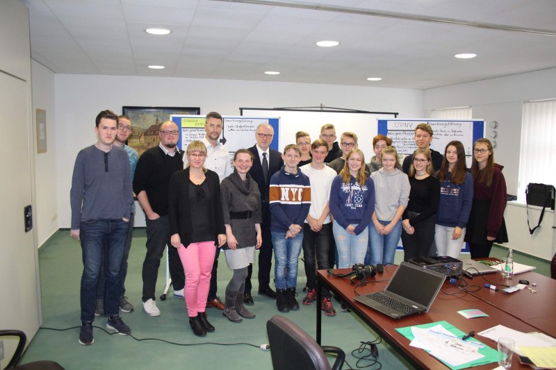 KI generiert: Das Bild zeigt eine Gruppe von Personen, die in einem Konferenzraum oder Klassenzimmer posieren. Der Hauptinhalt des Bildes ist eine Gruppenfotografie, bei der die Teilnehmer einer Veranstaltung oder eines Meetings gemeinsam fotografiert werden.