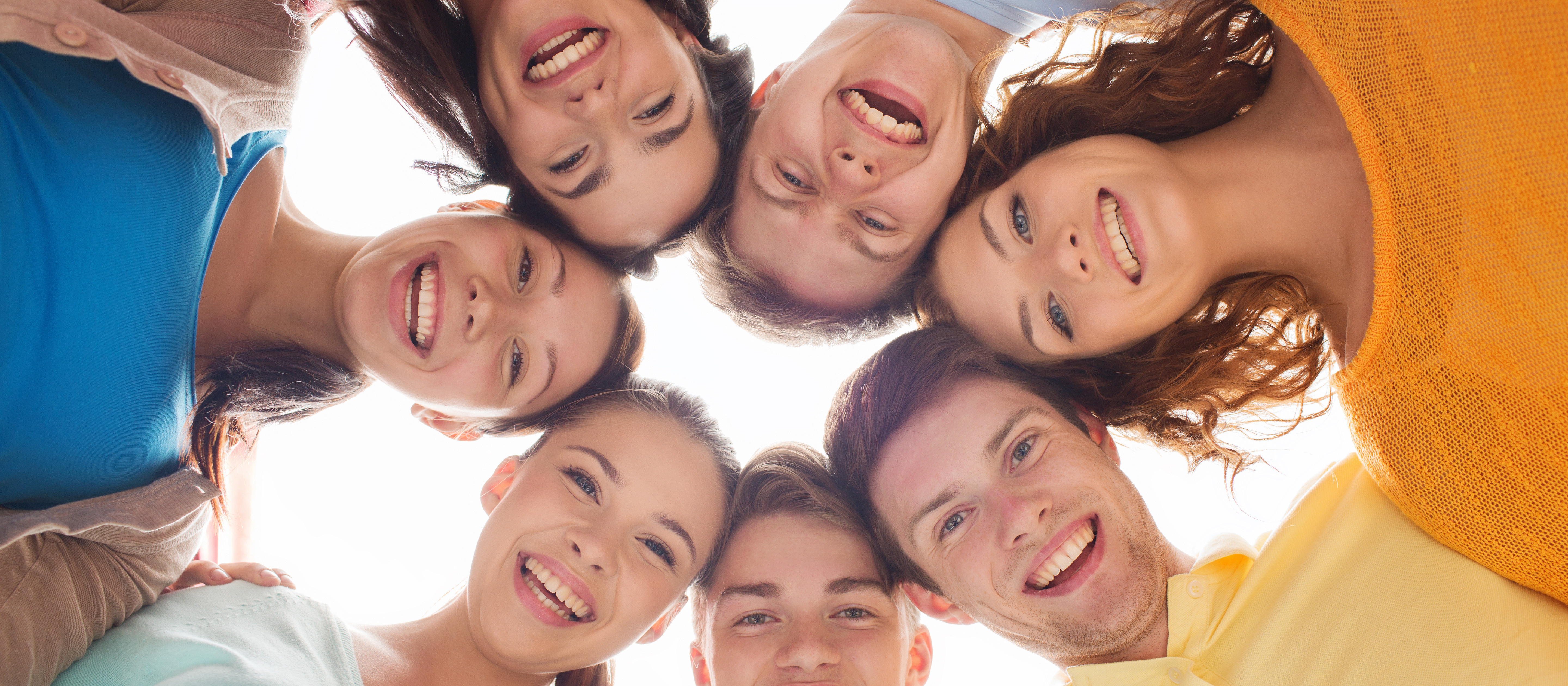 KI generiert: Das Bild zeigt eine Gruppe von sieben lächelnden jungen Menschen, die eng beieinanderstehen und gemeinsam in die Kamera schauen. Der Hauptinhalt des Bildes ist die Darstellung von Freundschaft und Gemeinschaft.
