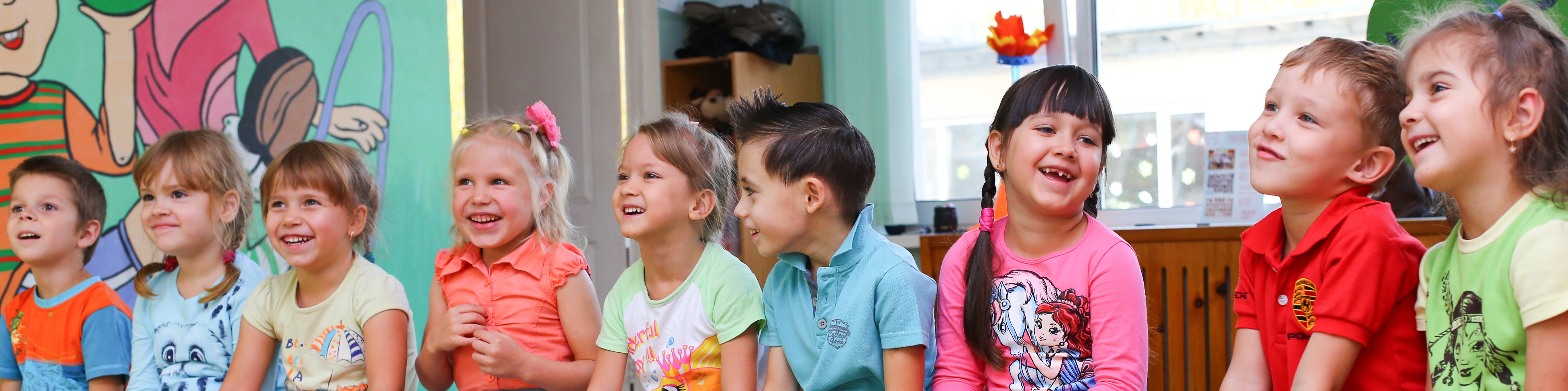 KI generiert: Das Bild zeigt eine Gruppe von Kindern, die fröhlich in einem Raum sitzen und sich unterhalten. Der Hauptinhalt des Bildes ist die Darstellung einer kindlichen, geselligen Atmosphäre.