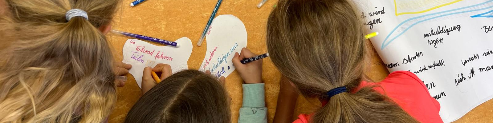 KI generiert: Das Bild zeigt drei Kinder, die an einem Tisch sitzen und auf Papier schreiben oder zeichnen. Der Hauptinhalt des Bildes ist eine kreative oder schulische Aktivität, bei der die Kinder sich auf ihre Aufgaben konzentrieren.