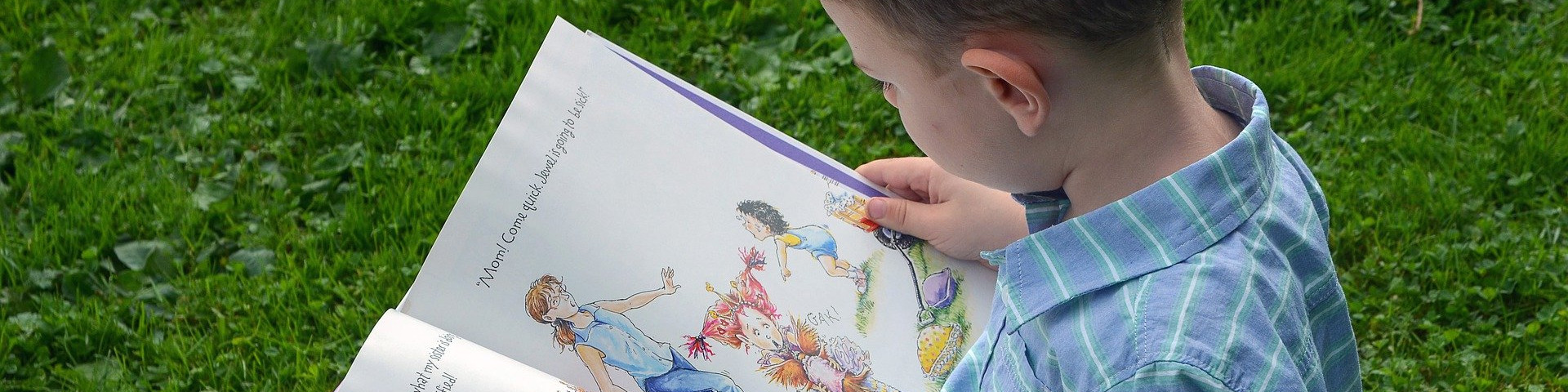 KI generiert: Das Bild zeigt einen Jungen, der auf dem Rasen sitzt und ein buntes Kinderbuch liest. Der Hauptinhalt des Bildes ist das Lesen und die kindliche Freude am Entdecken von Geschichten.