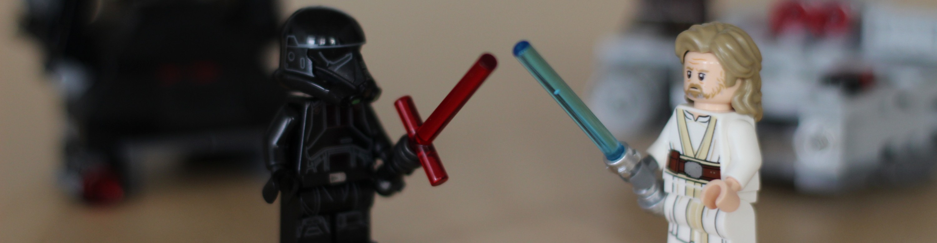 KI generiert: Das Bild zeigt zwei LEGO-Figuren, die ein Duell mit Lichtschwertern austragen. Eine Figur trägt ein dunkles Outfit mit einem roten Lichtschwert, die andere ein helles Outfit mit einem blauen Lichtschwert.