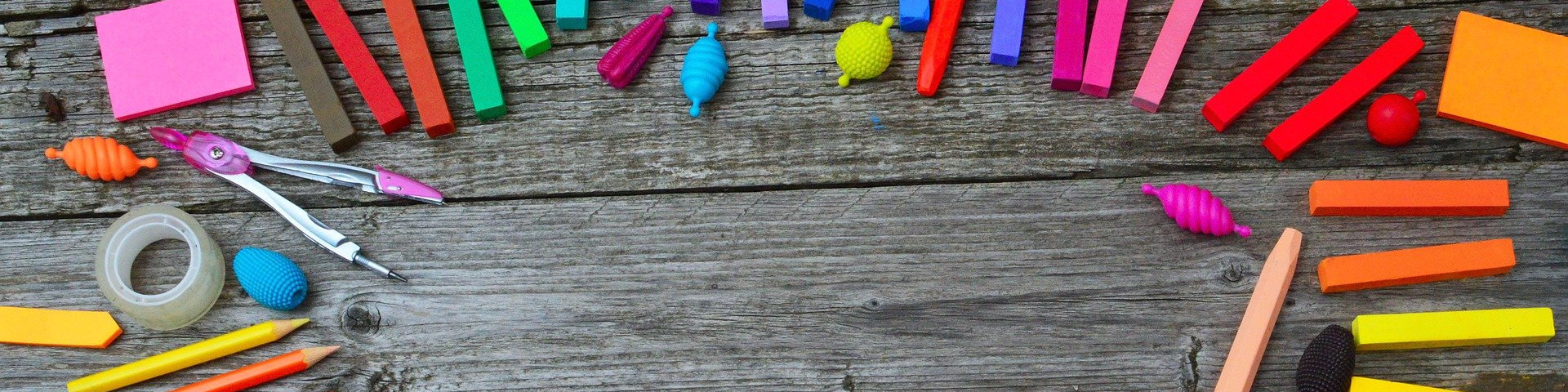 KI generiert: Das Bild zeigt eine bunte Ansammlung von Schul- und Bastelutensilien wie Stifte, Klebestift, Schere, Radiergummis und geometrische Formen auf einem rustikalen Holzhintergrund. Der Hauptinhalt des Bildes sind die verschiedenen farbenfrohen Gegenstände, die kreatives Arbeiten und Lernen symbolisieren.