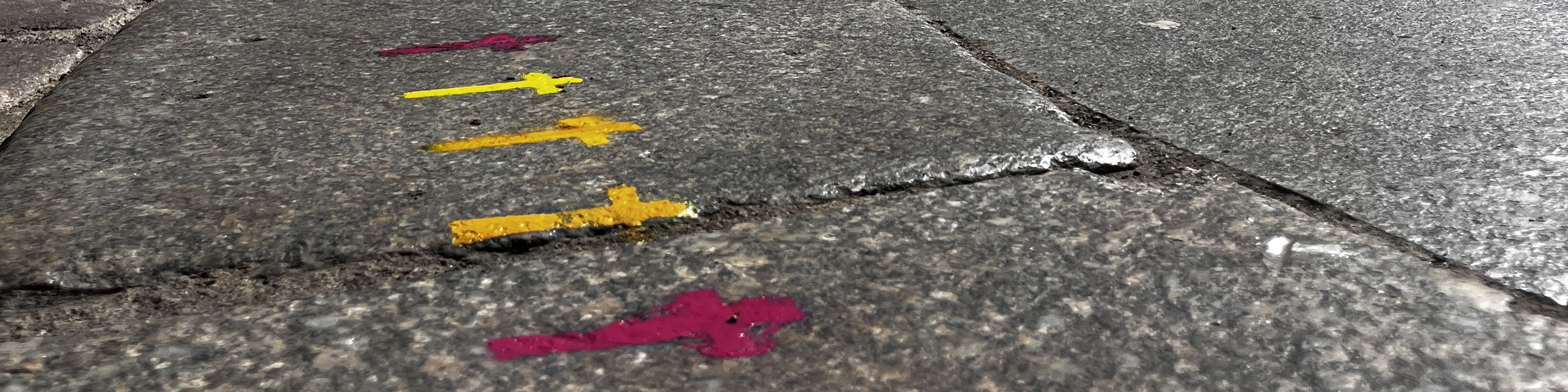 KI generiert: Das Bild zeigt einen gepflasterten Boden mit farbigen Pfeilen und Markierungen in Gelb und Pink. Die Pfeile und Markierungen scheinen als Wegweiser oder Hinweise zu dienen.