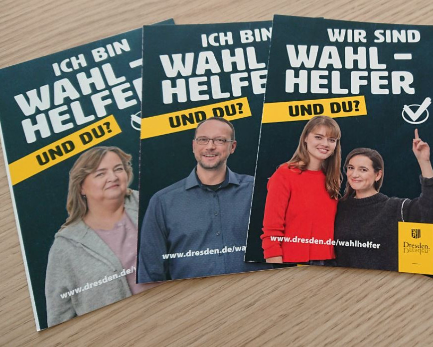 KI generiert: Das Bild zeigt mehrere Wahlplakate mit dem Slogan "Ich bin WAHLHELFER UND DU?" und einem Link zur Website www.dresden.de/wahlhelfer. Die Plakate fordern zur Teilnahme als Wahlhelfer auf und zeigen verschiedene Personen, die sich dafür engagieren.