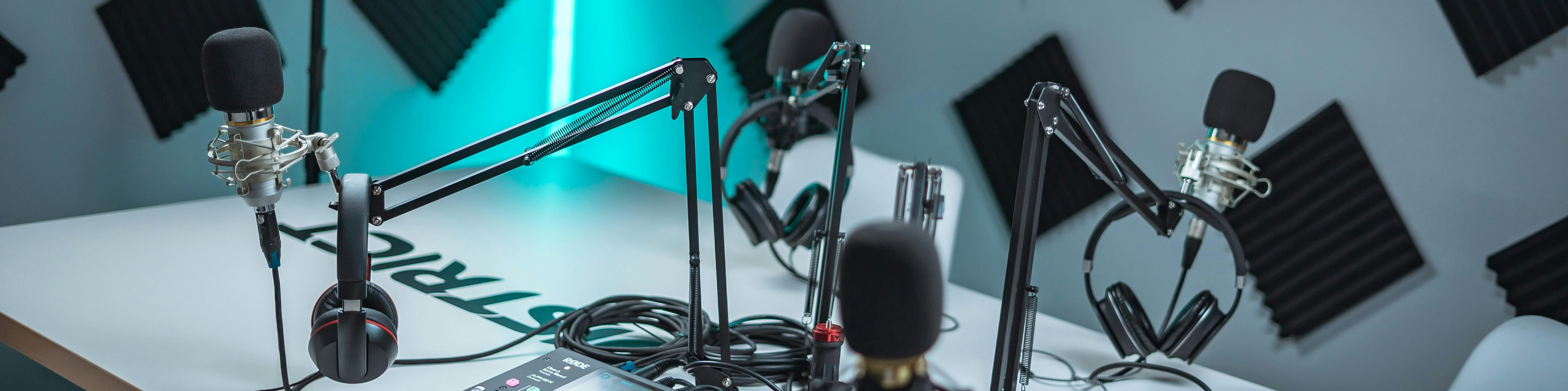 KI generiert: Das Bild zeigt ein professionelles Aufnahmestudio mit mehreren Mikrofonen, Kopfhörern und anderen Audioausrüstungen, die auf einem Tisch montiert sind. Der Hauptinhalt des Bildes ist die Ausrüstung für Radio- oder Podcast-Aufnahmen.