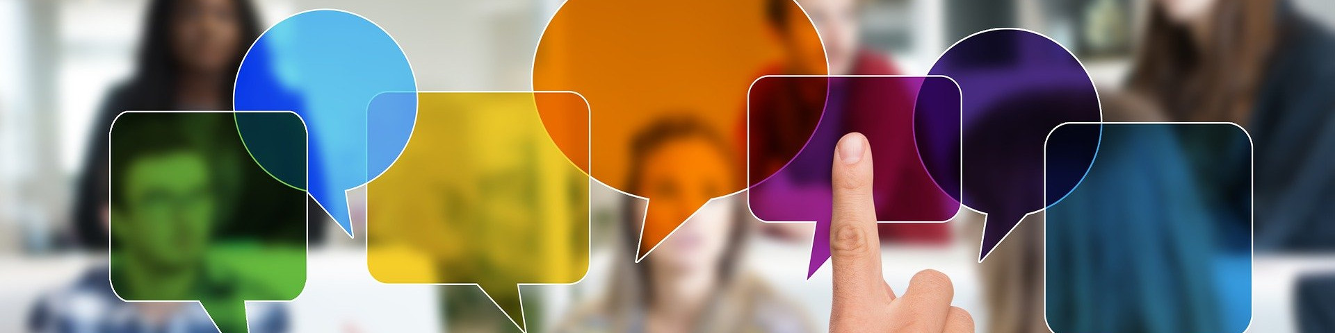 KI generiert: Das Bild zeigt eine Hand, die auf eine digitale, farbenfrohe Sprechblase tippt, umgeben von weiteren Sprechblasen in verschiedenen Farben. Im Hintergrund sind unscharf Personen zu erkennen, die möglicherweise an einer Diskussion oder einem Meeting teilnehmen. Der Hauptinhalt des Bildes ist die Darstellung von Kommunikation und Interaktion.