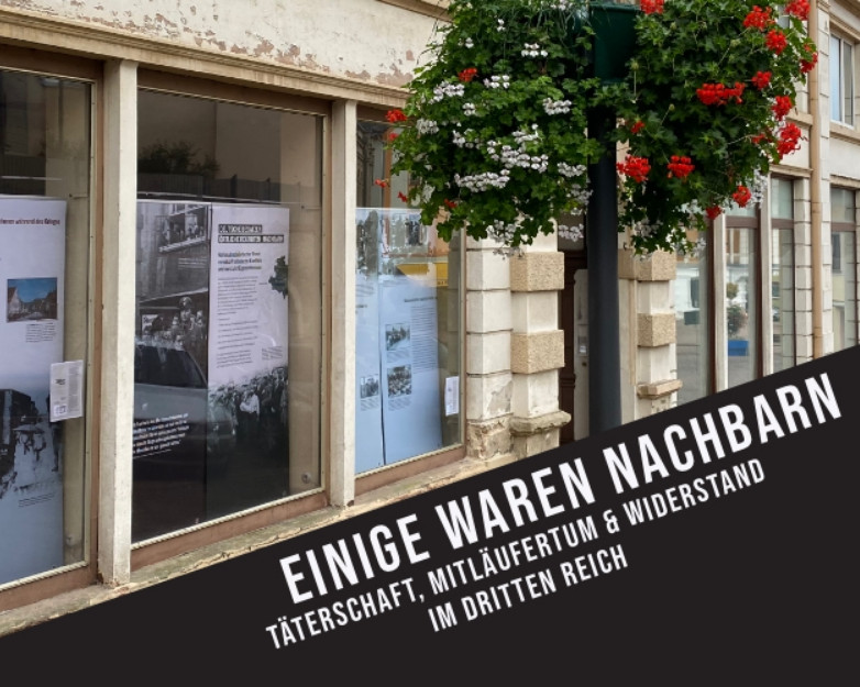 KI generiert: Das Bild zeigt eine Ausstellung in einem Museum oder einer Galerie mit dem Titel "Einige Waren Nachbarn: Täterschaft, Mittätertum & Widerstand im Dritten Reich". Der Hauptinhalt der Ausstellung scheint sich mit den Rollen und Handlungen von Personen während der Zeit des Nationalsozialismus zu befassen.