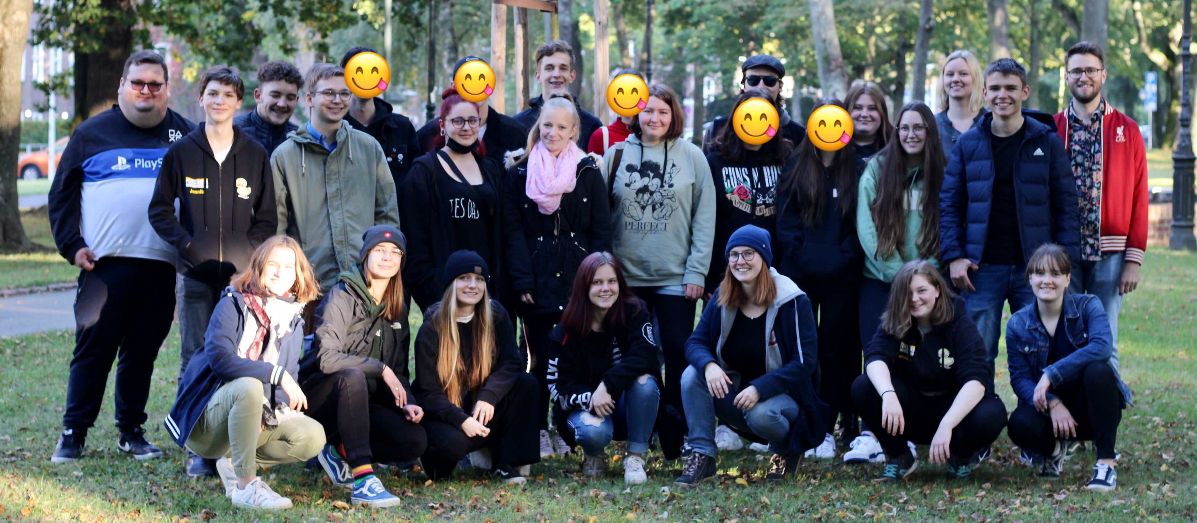 KI generiert: Das Bild zeigt eine Gruppe von Personen, die in einem Park posieren und gemeinsam ein Foto machen. Der Hauptinhalt des Bildes ist die Gruppe von Menschen, die in einer entspannten Atmosphäre zusammenkommen.