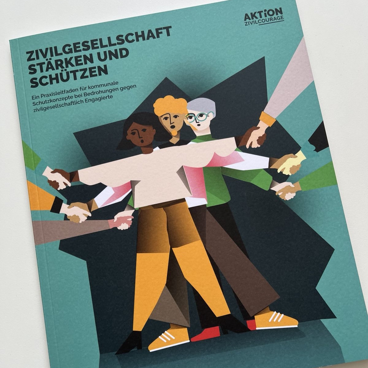 KI generiert: Das Bild zeigt das Cover eines Buches mit dem Titel "Zivilgesellschaft stärken und schützen" von "Aktion Zivilcourage". Es enthält eine Illustration von vier Personen, die sich an den Händen halten, was Gemeinschaft und Solidarität symbolisiert.