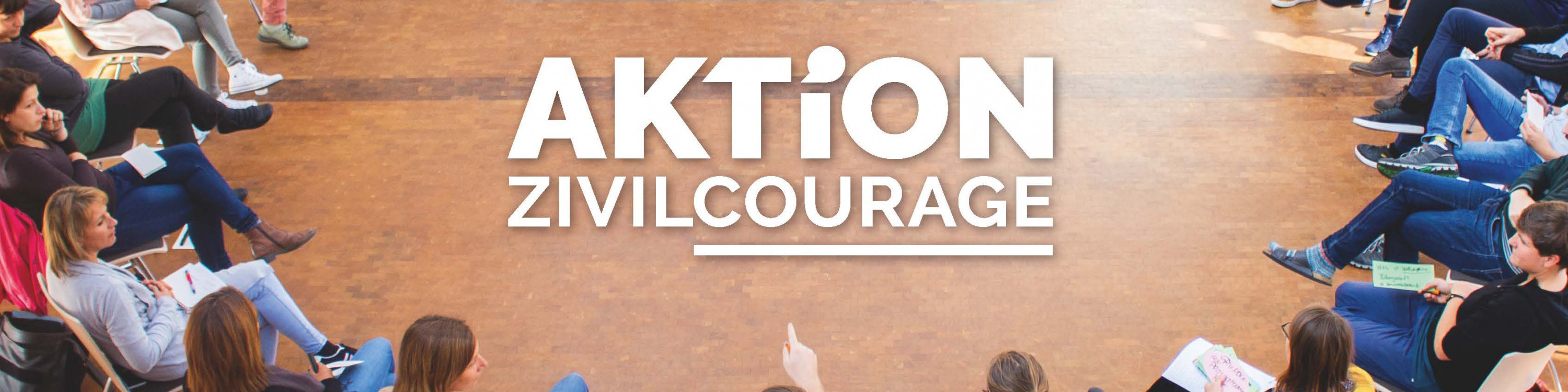 KI generiert: Das Bild zeigt eine Gruppe von Menschen, die in einem Kreis auf dem Boden sitzen und sich anscheinend unterhalten oder einer Aktivität widmen. Im Zentrum des Bildes steht der Text "AKTiON ZIVILCOURAGE".