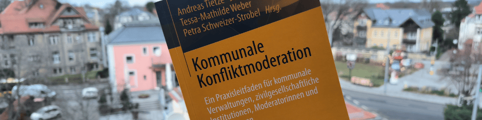 KI generiert: Das Bild zeigt ein Buch mit dem Titel "Kommunale Konfliktmoderation" von Andreas Flietner, Tessa-Mathilde Weber und Petra Schweizer-Strobel, das vor einer verschneiten Stadtlandschaft mit Häusern und einer Straße liegt. Der Hauptinhalt des Bildes ist das Buch, das sich mit kommunaler Konfliktmoderation in Verwaltungen, zivilgesellschaftlichen Institutionen und Unternehmen befasst.