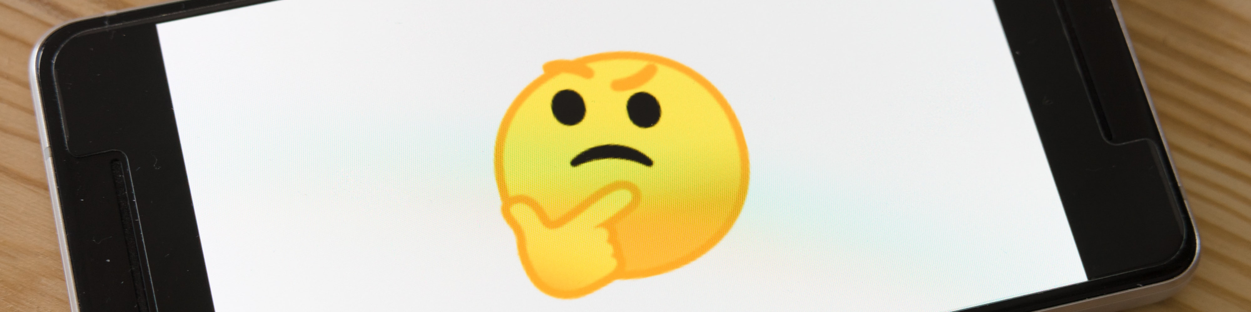 KI generiert: Das Bild zeigt ein Smartphone-Display mit einem nachdenklichen Emoji, das die Hände unter dem Kinn verschränkt hat. Der Hauptinhalt des Bildes ist das Emoji auf dem Bildschirm des Smartphones.