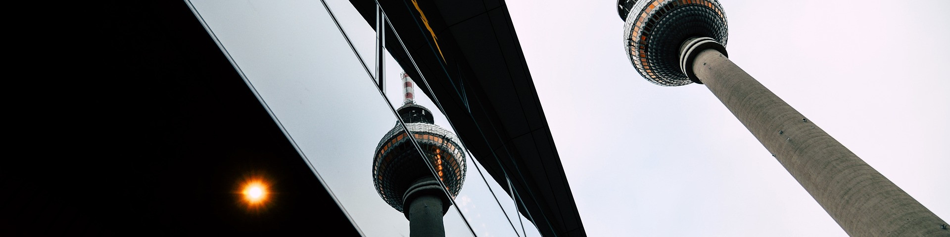 KI generiert: Das Bild zeigt den Fernsehturm am Alexanderplatz in Berlin, der sich in der Fassade eines modernen Gebäudes spiegelt. Der Hauptinhalt des Bildes ist die architektonische Kombination aus dem Fernsehturm und dem Gebäude, das ihn reflektiert.