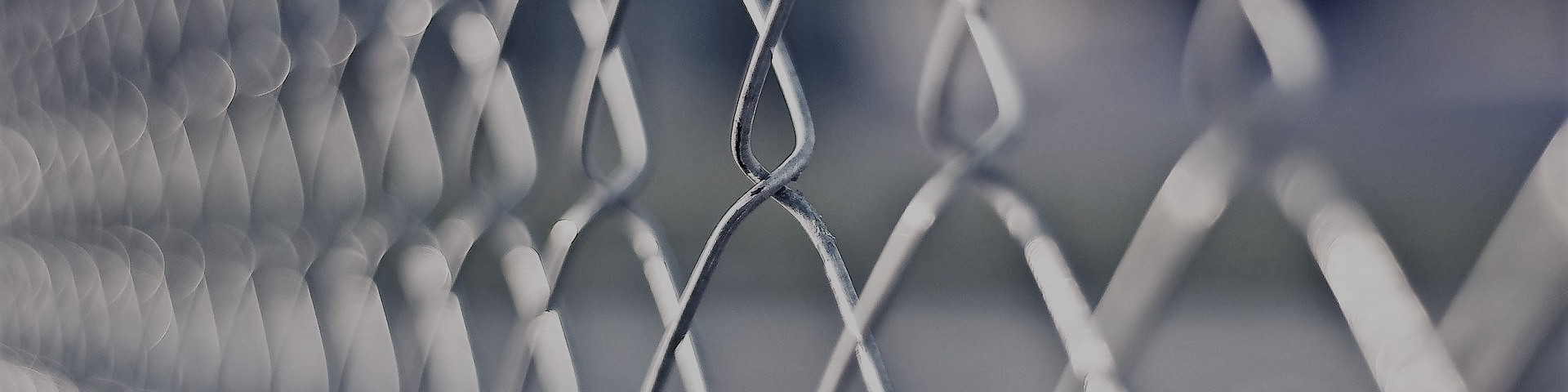 KI generiert: Das Bild zeigt eine Nahaufnahme eines Metallzauns mit einer komplexen, gitterartigen Struktur. Der Hauptinhalt des Bildes ist der Zaun selbst, der durch die Unschärfe im Hintergrund besonders hervorgehoben wird.