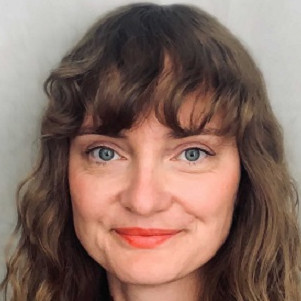 KI generiert: Das Bild zeigt eine Person mit welligem, braunem Haar und blauen Augen, die in die Kamera lächelt. Der Hauptinhalt des Bildes ist das Porträt dieser Person.