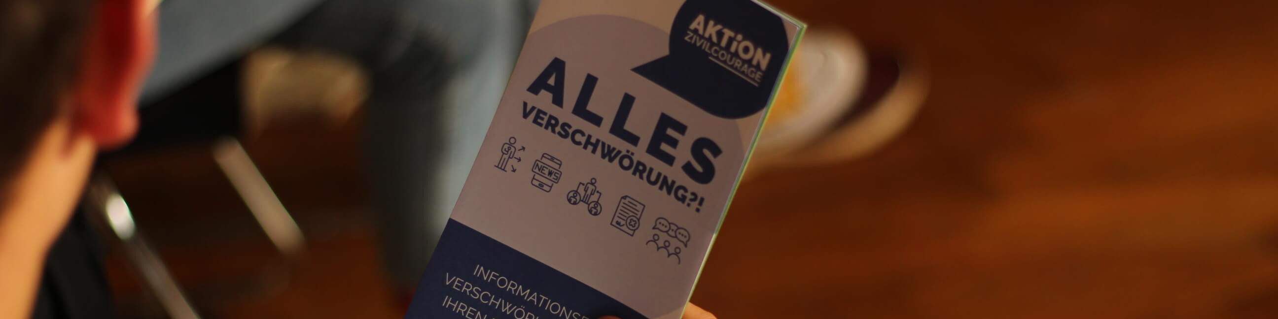 KI generiert: Das Bild zeigt eine Hand, die ein Informationsblatt mit dem Titel "AKTION GRUNDWASSERSCHUTZ" hält, auf dem die Frage "ALLES VERSCHWÖRUNG?!" zu lesen ist. Der Hauptinhalt des Bildes ist das Informationsblatt, das sich mit dem Thema Verschwörungstheorien im Kontext des Grundwasserschutzes beschäftigt.