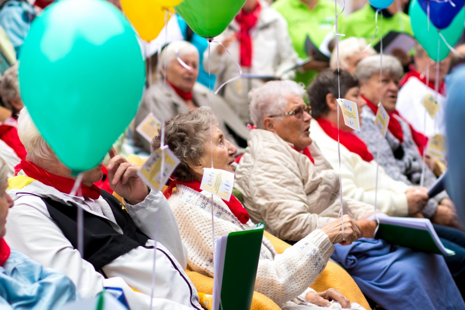 KI generiert: Das Bild zeigt eine Gruppe älterer Menschen, die auf Stühlen sitzen und an einer Veranstaltung teilnehmen, bei der sie bunte Ballons in den Händen halten. Der Hauptinhalt des Bildes ist die fröhliche und gesellige Atmosphäre unter den Senioren.