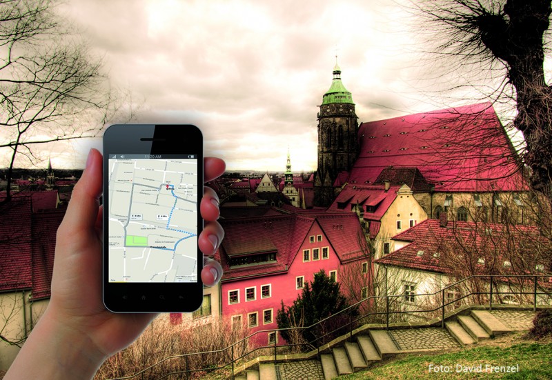 KI generiert: Das Bild zeigt eine Hand, die ein Smartphone mit einer Kartenanwendung hält, vor dem Hintergrund einer malerischen Stadtlandschaft mit historischen Gebäuden und einer Kirche. Der Hauptinhalt des Bildes ist die Kombination von moderner Technologie (Smartphone-Navigation) und traditioneller Architektur.