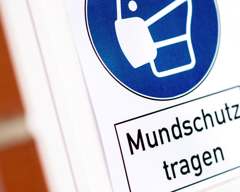KI generiert: Das Bild zeigt ein Schild mit der Aufschrift "Mundschutz tragen". Der Hauptinhalt des Bildes ist die Aufforderung, einen Mundschutz zu tragen, was auf eine Maßnahme zur Infektionsprävention hinweist.
