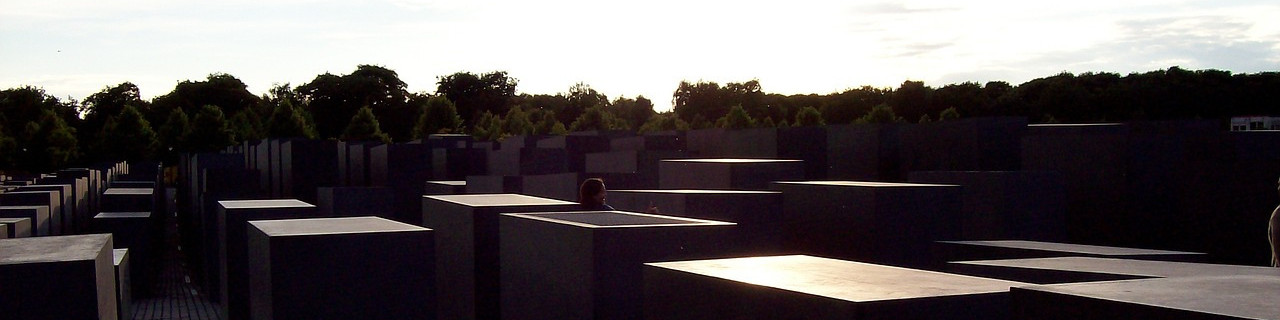 KI generiert: Das Bild zeigt das Holocaust-Mahnmal in Berlin, auch bekannt als "Denkmal für die ermordeten Juden Europas". Es besteht aus zahlreichen grauen Betonblöcken unterschiedlicher Höhen, die in einem wellenförmigen Muster angeordnet sind, mit Bäumen im Hintergrund.