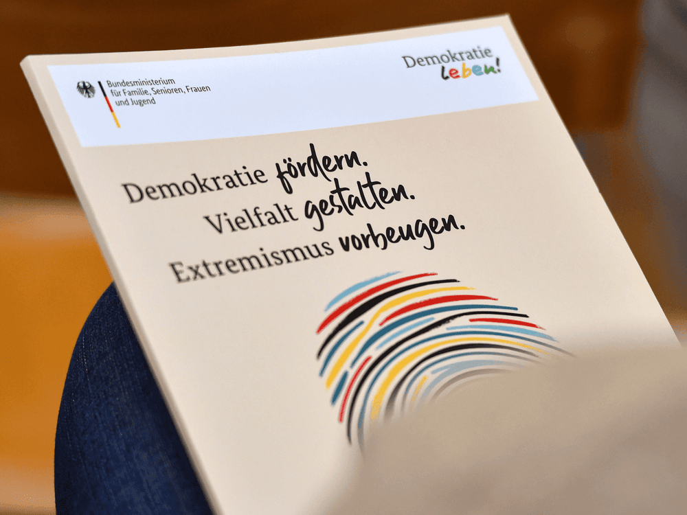KI generiert: Das Bild zeigt einen Ausschnitt eines Dokuments oder einer Broschüre mit dem Text "Demokratie fördern. Vielfalt gestalten. Extremismus vorbeugen." Der Hauptinhalt des Bildes ist die Förderung von Demokratie und Vielfalt sowie die Prävention von Extremismus.