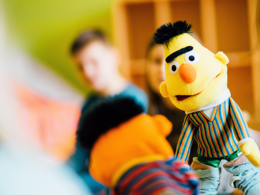 KI generiert: Das Bild zeigt eine Gruppe von Kindern, die fröhlich in einem Raum sitzen und sich unterhalten. Der Hauptinhalt des Bildes ist die Darstellung einer kindlichen, geselligen Atmosphäre.