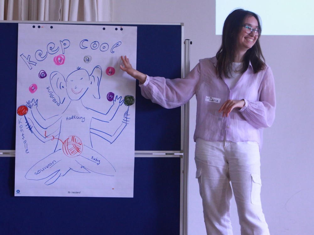 KI generiert: Das Bild zeigt eine Gruppe von Personen in einem Seminarraum, wobei eine Person vorne steht und eine Präsentation hält, während die anderen zuhören. Der Hauptinhalt des Bildes ist eine Bildungs- oder Schulungsveranstaltung.