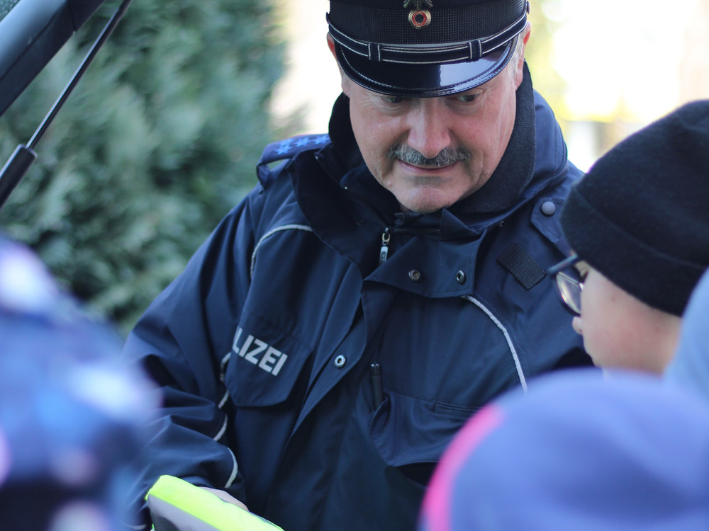KI generiert: Das Bild zeigt eine Person, die einer anderen Person, die auf dem Boden sitzt, die Hände mit einem Seil oder einer Schnur zusammenbindet. Die Szene scheint eine Art von Festnahme oder Kontrolle darzustellen.