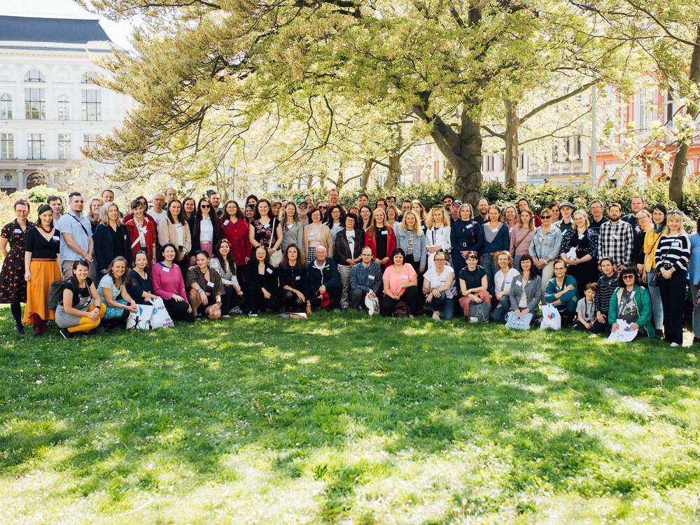 KI generiert: Das Bild zeigt eine Gruppe von Personen, die sich in einer Versammlung oder einem Seminar befinden, wobei eine Frau ein Mikrofon hält und möglicherweise spricht oder eine Frage stellt. Der Hauptinhalt des Bildes ist die Interaktion und Kommunikation zwischen den Teilnehmern in einer öffentlichen oder halboffentlichen Veranstaltung.