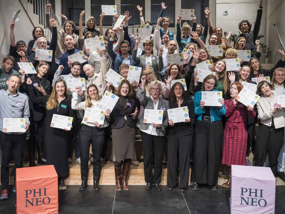 KI generiert: Das Bild zeigt eine Gruppe von Personen, die stolz ihre Zertifikate präsentieren, während eine Frau in der Mitte ein Mikrofon hält und möglicherweise eine Rede hält. Der Hauptinhalt des Bildes ist eine Zertifikatsübergabezeremonie.