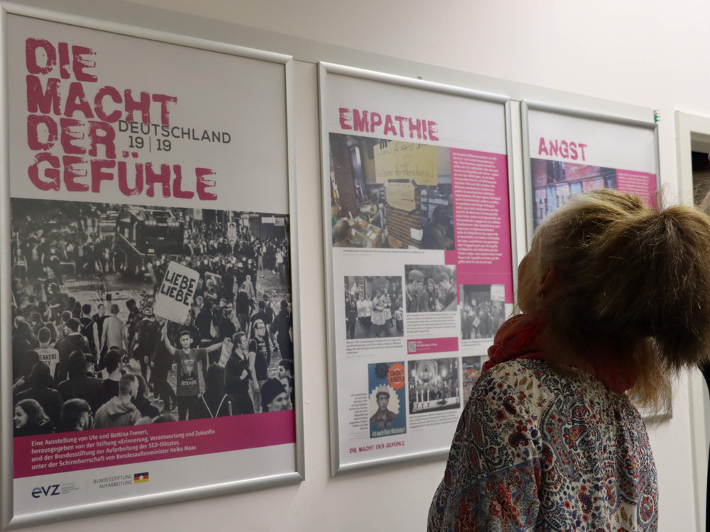 KI generiert: Das Bild zeigt eine Ausstellung mit Postern und Informationen über die Themen "Empathie" und "Angst". Im Vordergrund sind zwei Personen, die sich die Ausstellungsstücke ansehen, während im Hintergrund ein großes Poster mit dem Titel "Macht der Gefühle Deutschland 19 | 19" zu sehen ist.