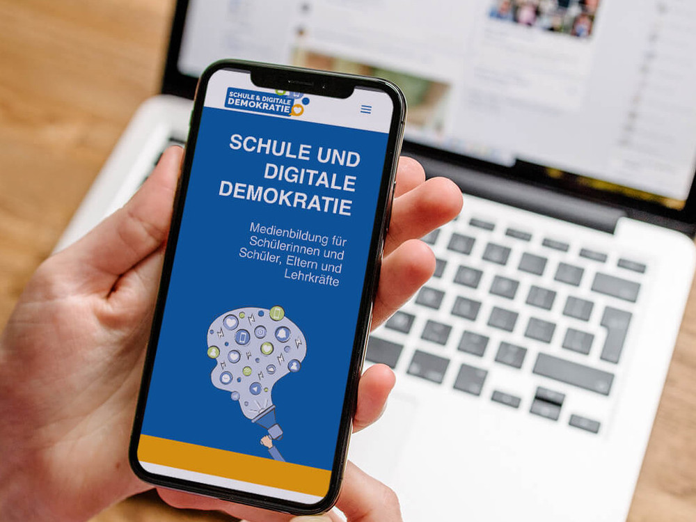 KI generiert: Das Bild zeigt zwei Jugendliche, die auf einer Bank sitzen und intensiv auf ihre Smartphones schauen. Der Hauptinhalt des Bildes ist die Nutzung von Mobiltelefonen durch die Jugendlichen.