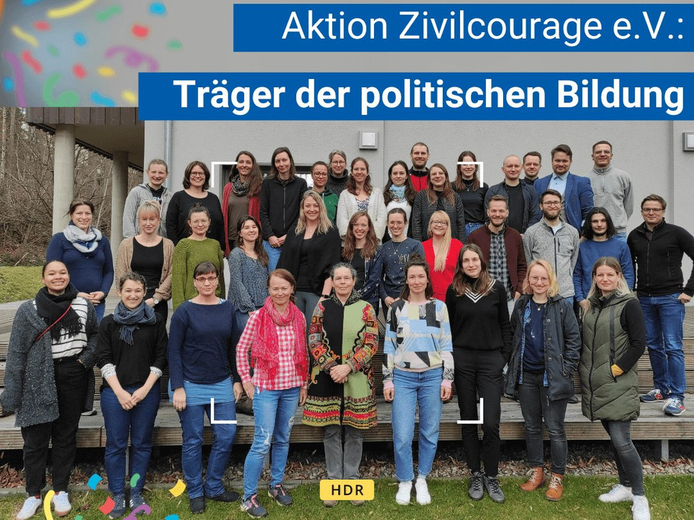 KI generiert: Das Bild zeigt eine große Gruppe von Menschen, die vor einem Gebäude posieren. Der Hauptinhalt des Bildes ist eine Gruppenfotografie, die vermutlich an einem offiziellen oder geselligen Anlass aufgenommen wurde.