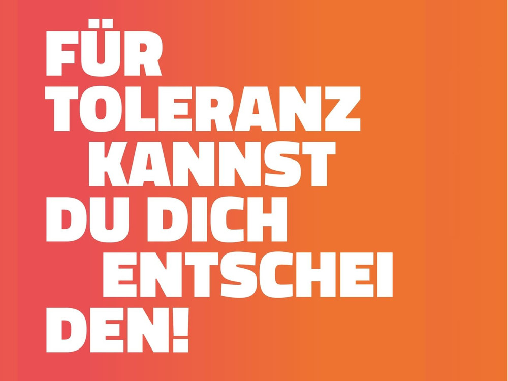 KI generiert: Das Bild zeigt eine abendliche Szene mit einem beleuchteten, bunten Pavillon auf einem Platz, der als "Toleranz Räume" beschriftet ist. Der Hauptinhalt des Bildes ist der Pavillon, der Kunstwerke und Informationen präsentiert und zum Betreten einlädt.