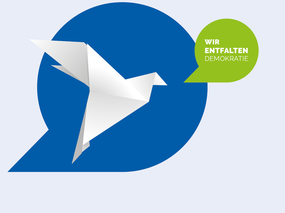 KI generiert: Das Bild zeigt ein weißes Origami-Vogel-Symbol auf einem blauen Hintergrund mit einer grünen Sprechblase, die den Text "Wir entfalten Demokratie" enthält. Der Hauptinhalt des Bildes ist die symbolische Darstellung von Demokratie durch den Origami-Vogel und den begleitenden Text.