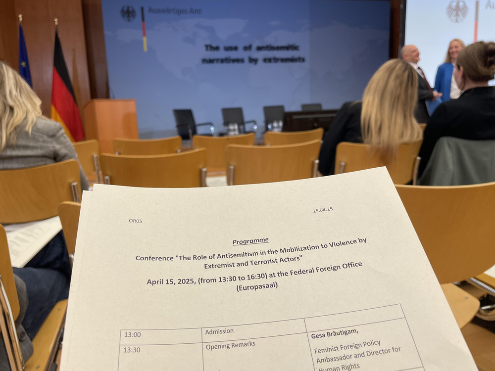KI generiert: Das Bild zeigt ein Programm für eine Konferenz mit dem Titel "The Role of Antisemitism in the Mobilization to Violence by Extremist and Terrorist Actors", die am 15. April 2025 von 13:30 bis 16:30 im Bundeshaus (Europasaal) stattfindet. Der Hauptinhalt des Bildes ist die Ankündigung dieser Konferenz und deren Details.