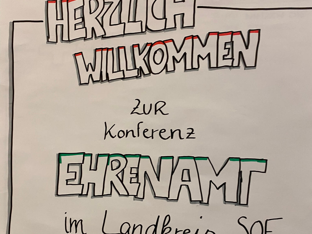 KI generiert: Das Bild zeigt eine Gruppe von Menschen, die an langen, mit Papier und Stiften bedeckten Tischen sitzen und sich in einer hellen, geräumigen Halle unterhalten. Der Hauptinhalt des Bildes ist eine Besprechung oder ein Workshop, bei dem die Teilnehmer gemeinsam arbeiten und diskutieren.