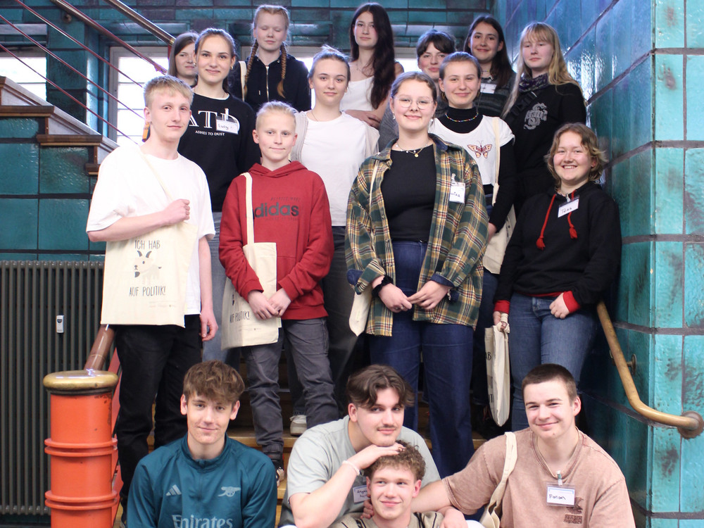 KI generiert: Das Bild zeigt eine Gruppe von fünf Personen, die in einem modernen, gut beleuchteten Innenraum auf bequemen Sitzen zusammenkommen und sich unterhalten. Der Hauptinhalt des Bildes ist eine gesellige Runde, die in entspannter Atmosphäre miteinander kommuniziert.