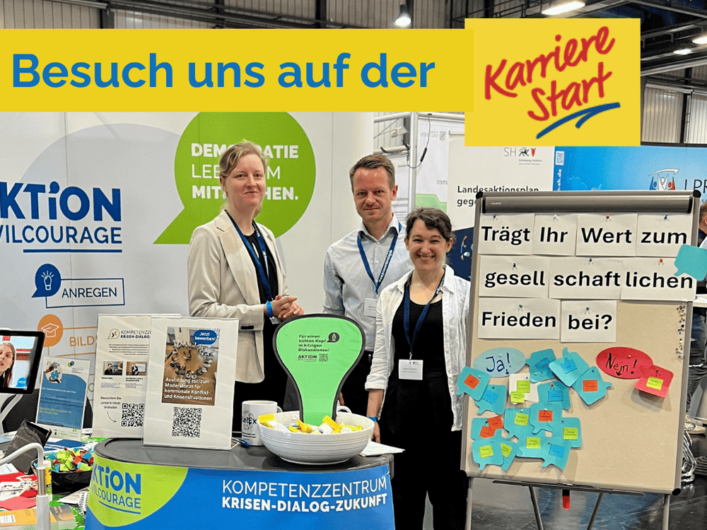 KI generiert: Das Bild zeigt drei Personen, die vor einem Stand mit dem Schriftzug "Aktion Zivilcourage" und einem Slogan zur Demokratie stehen. Im Hintergrund sind Informationsmaterialien und ein Bildschirm mit dem Text "Trägt Ihr Wert zum gesellschaftlichen Leben bei?" zu sehen.