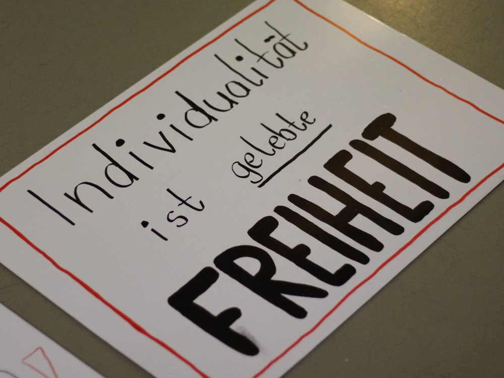 KI generiert: Das Bild zeigt eine Gruppe junger Männer in einem Innenraum, die sich zu unterhalten scheinen. Der Hauptinhalt des Bildes ist die Interaktion und das Gespräch zwischen den Personen.