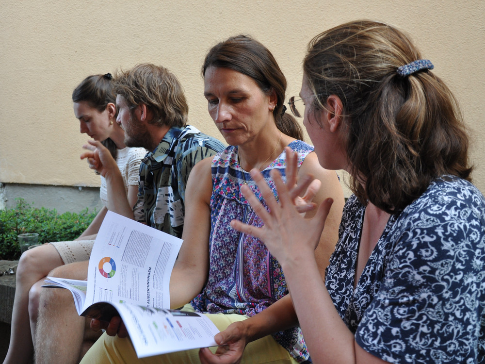 KI generiert: Das Bild zeigt eine Gruppe von Kindern, die gemeinsam an einem großen Blatt Papier arbeiten und verschiedene Begriffe darauf schreiben oder malen. Der Hauptinhalt des Bildes ist eine kreative Gruppenarbeit oder ein Brainstorming, bei dem die Kinder Ideen sammeln und visuell darstellen.