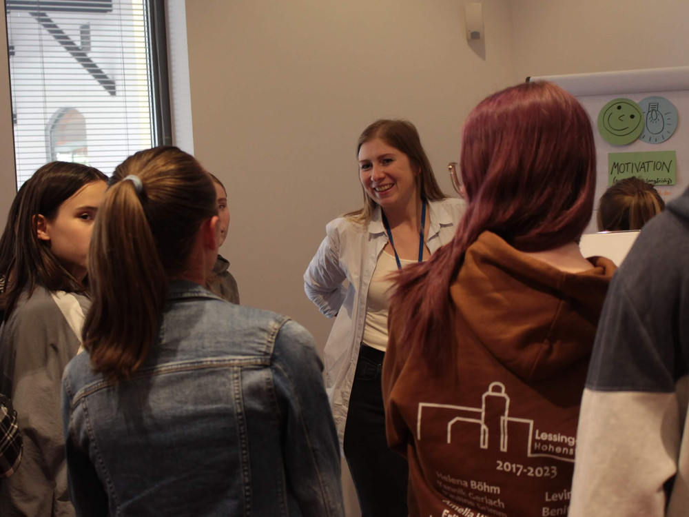 KI generiert: Das Bild zeigt eine Gruppe von Personen, die in einem Innenraum stehen und sich unterhalten. Es scheint sich um eine informelle Zusammenkunft oder ein Netzwerktreffen zu handeln, bei dem die Teilnehmer in Gespräche vertieft sind.